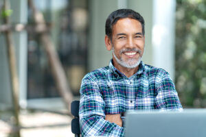 older man smiling with laptop