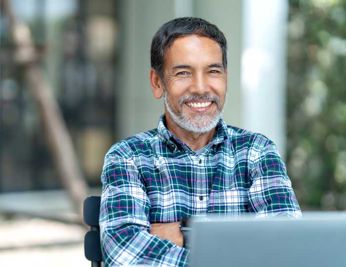 Man, smiling, with a laptop in front of him