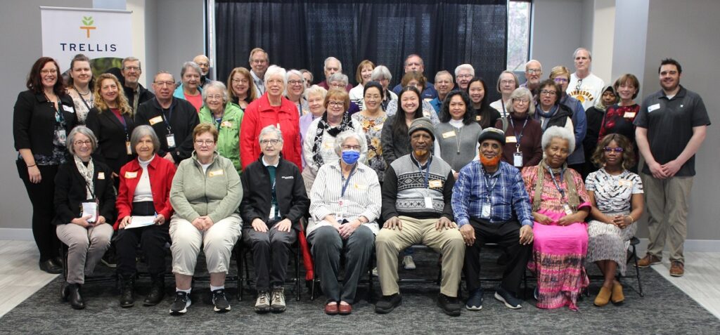 A photo of approximately 40 people posing together in front of a Trellis banner.