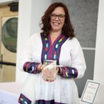 Photo of a person holding an award made of glass.