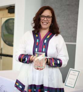 Photo of a person holding an award made of glass.