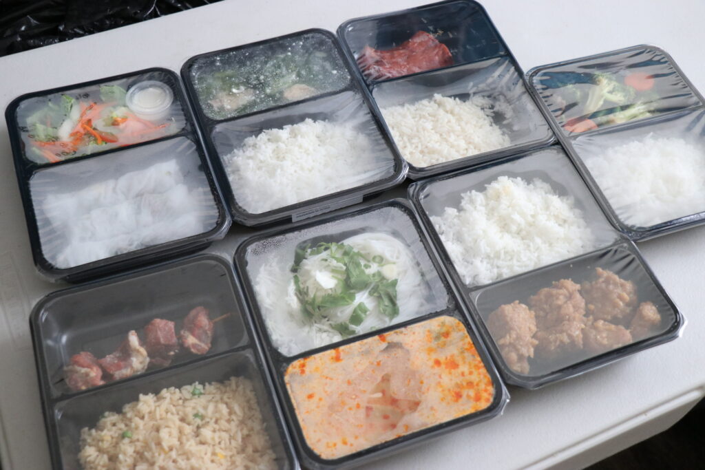 Photo of seven packaged meals in microwavable trays.