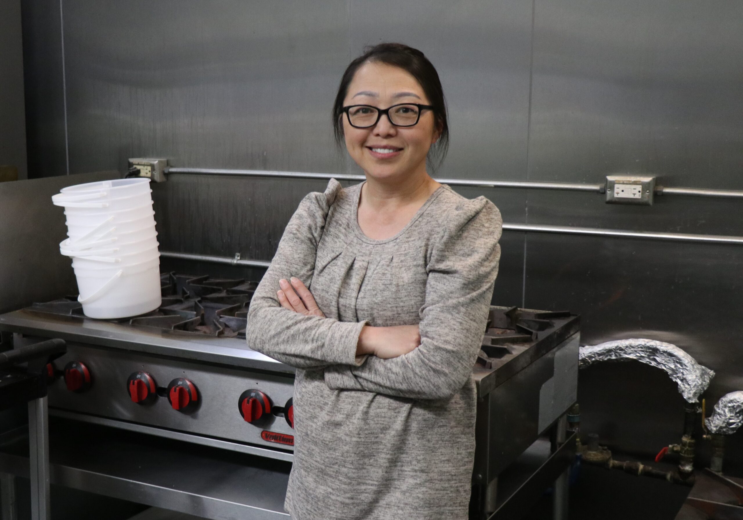 Photo of May Vang in front of a commercial stove.