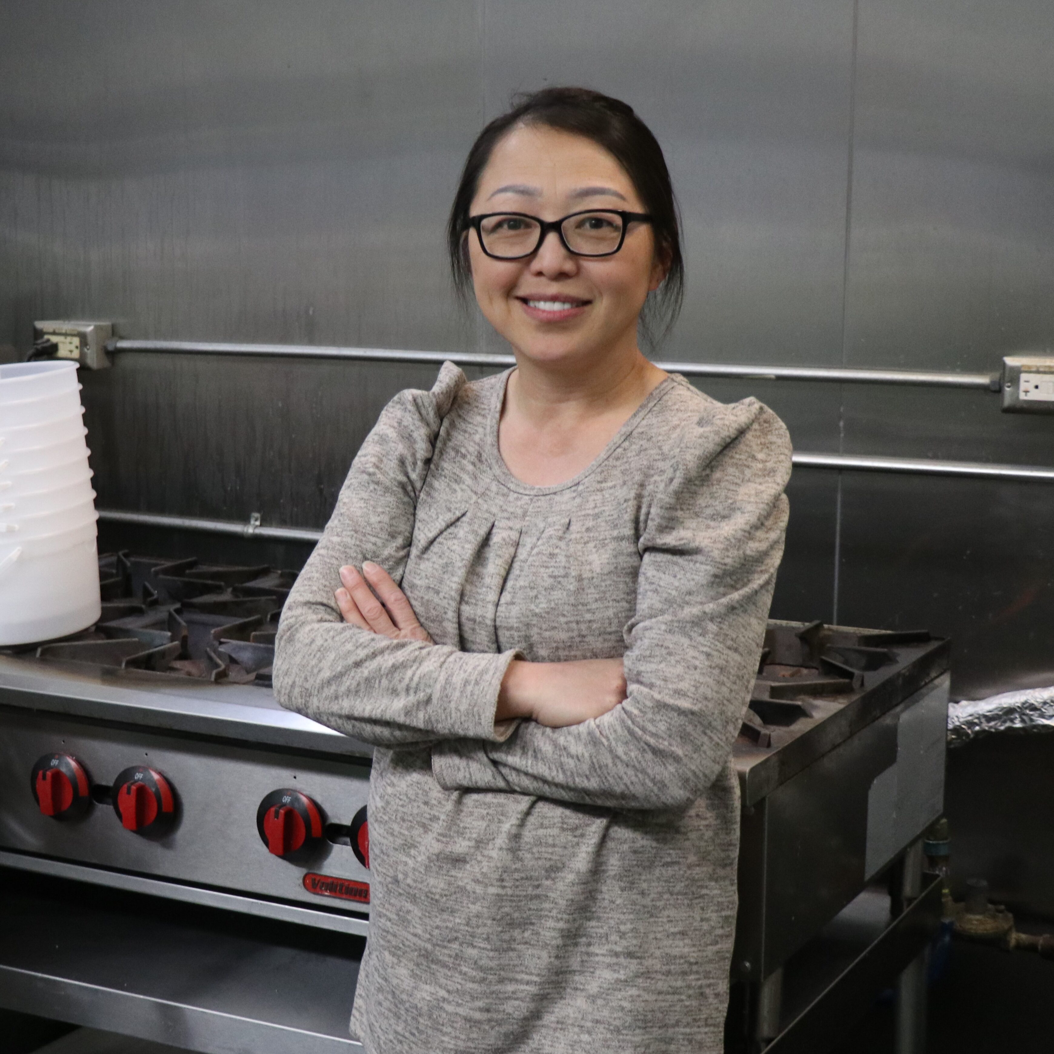 Photo of May Vang in front of a commercial stove.