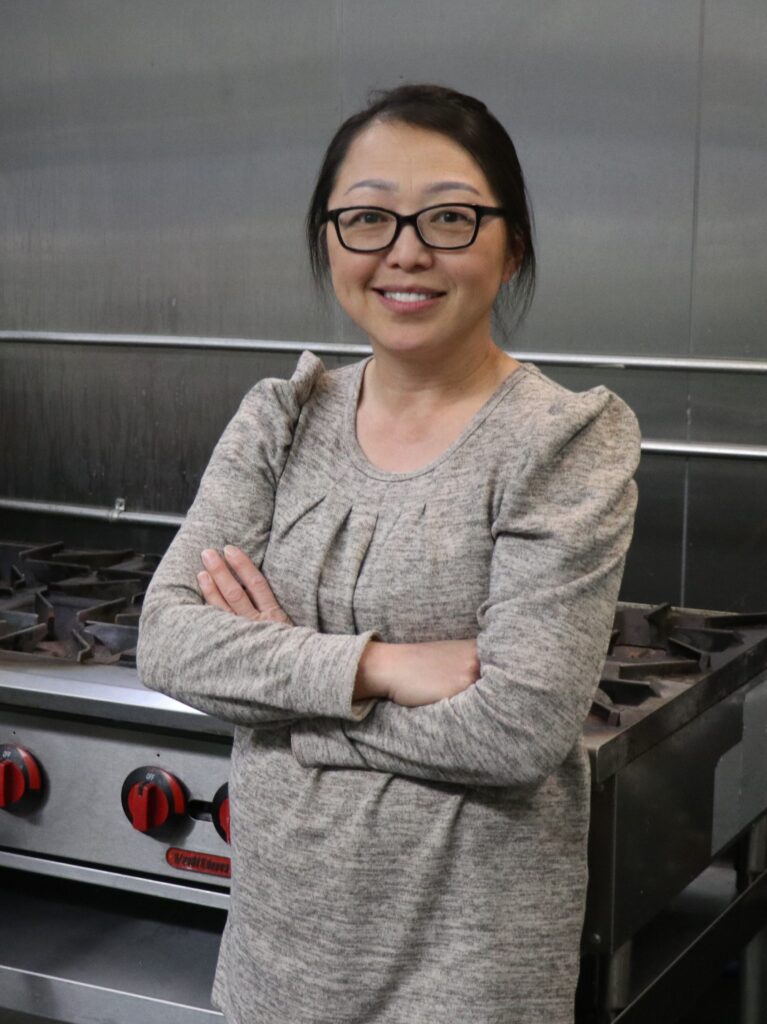 Photo of May Vang in front of a commercial stove.