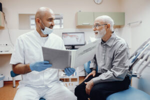 Photo of a dentist speaking with a patient in an exam room.