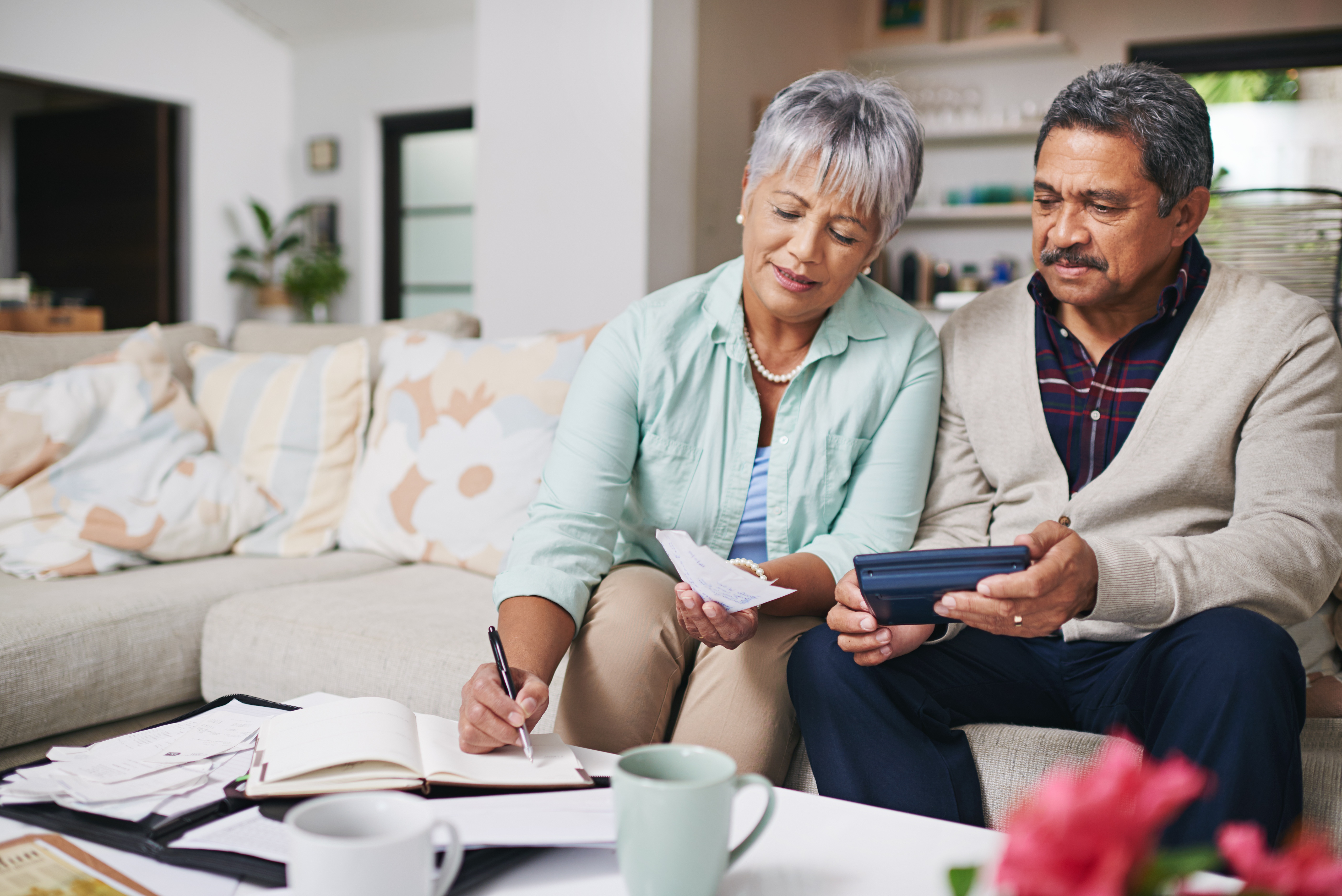 Photo of two people sitting on a couch paying bills.