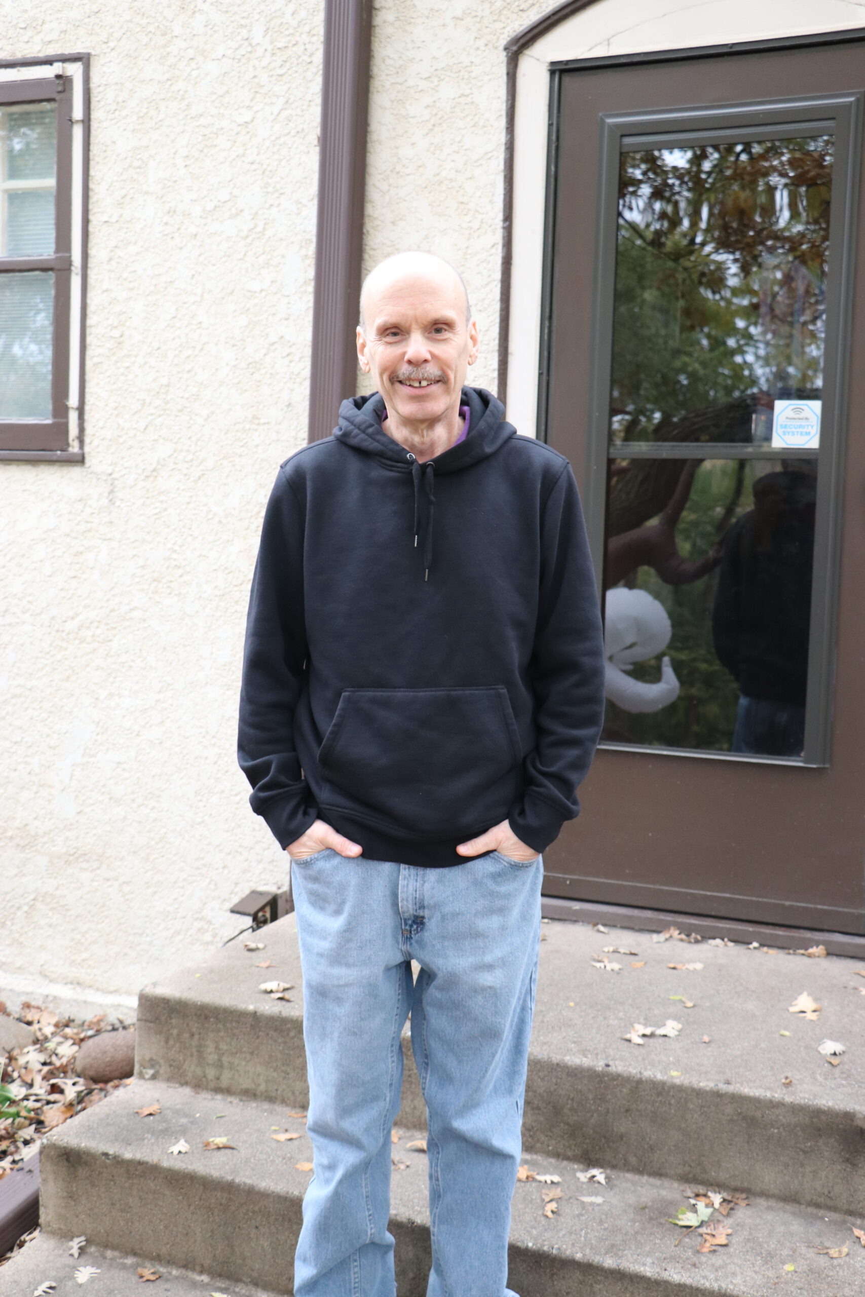 Photo of a person standing on the front steps of their home.