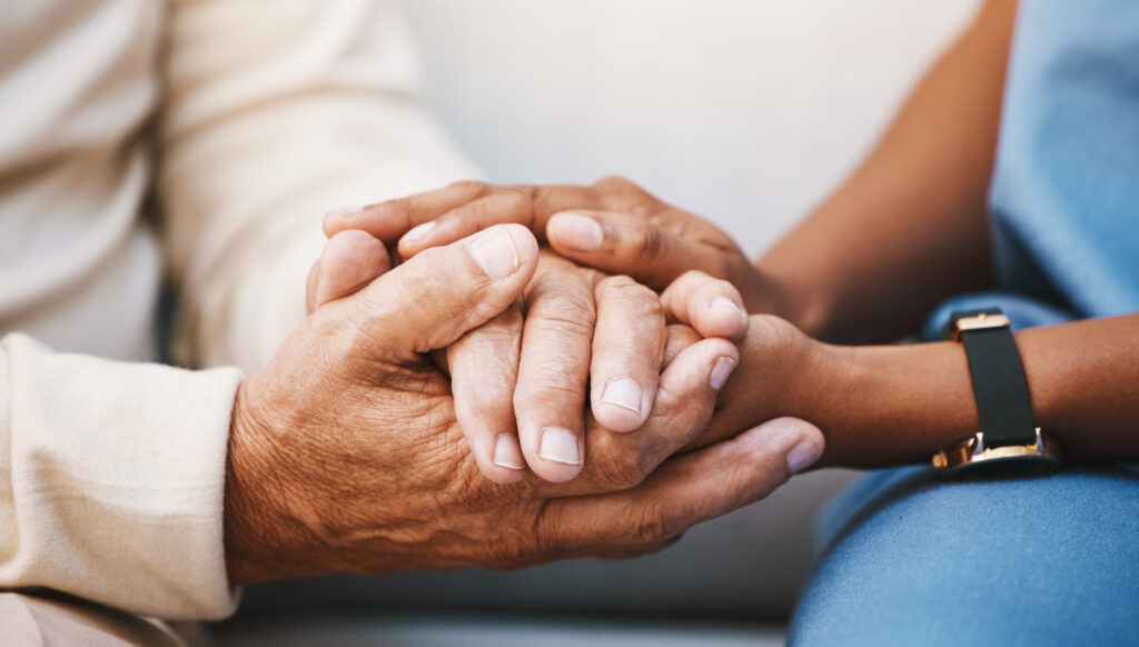 Close up photo of two people holding hands. 