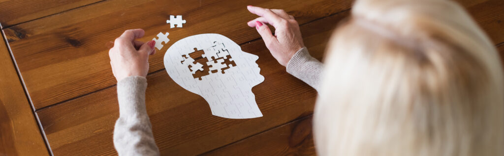 Photo of a person putting together a puzzle shaped like a human head.