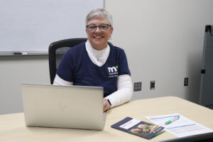 Photo of Jill Lord sitting at a desk in front of a laptop.