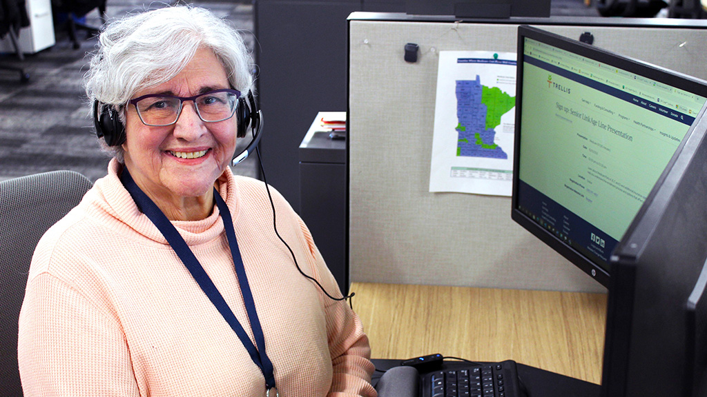 Photo of a woman sitting at a computer desk wearing a headset.