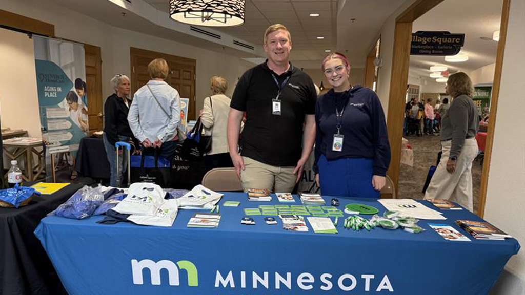 Photo of two Minnesota Aging Pathways staff at an information table indoors.