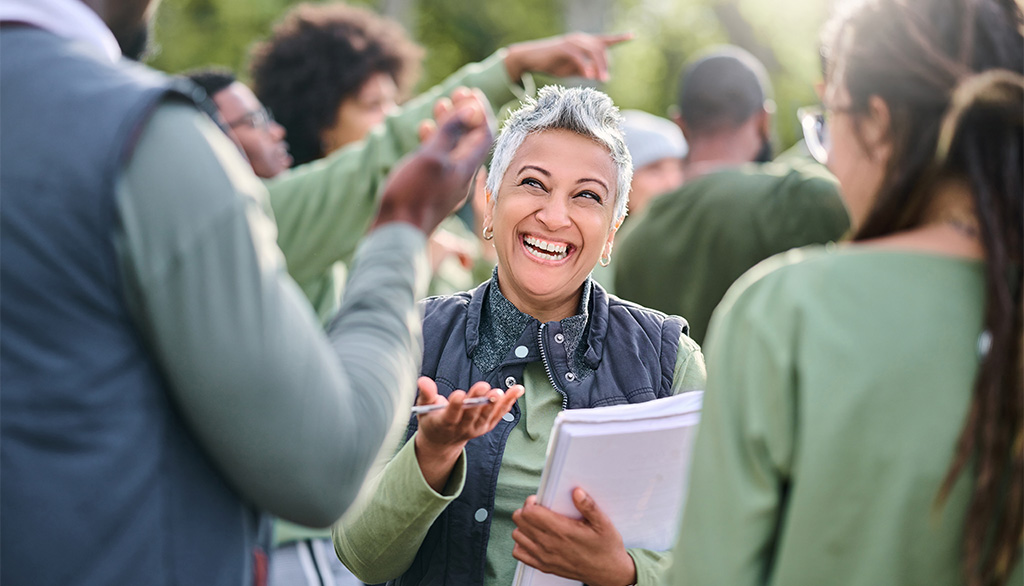 Photo of a woman speaking with two people outdoors.